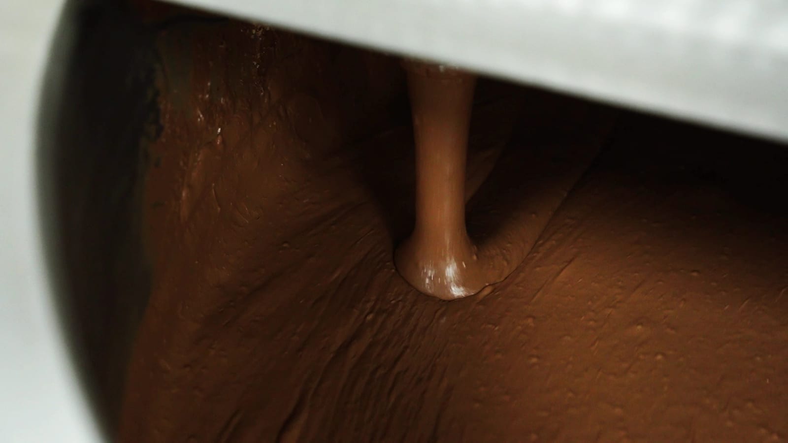 Melted chocolate flowing into the melting tank at the EDC factory