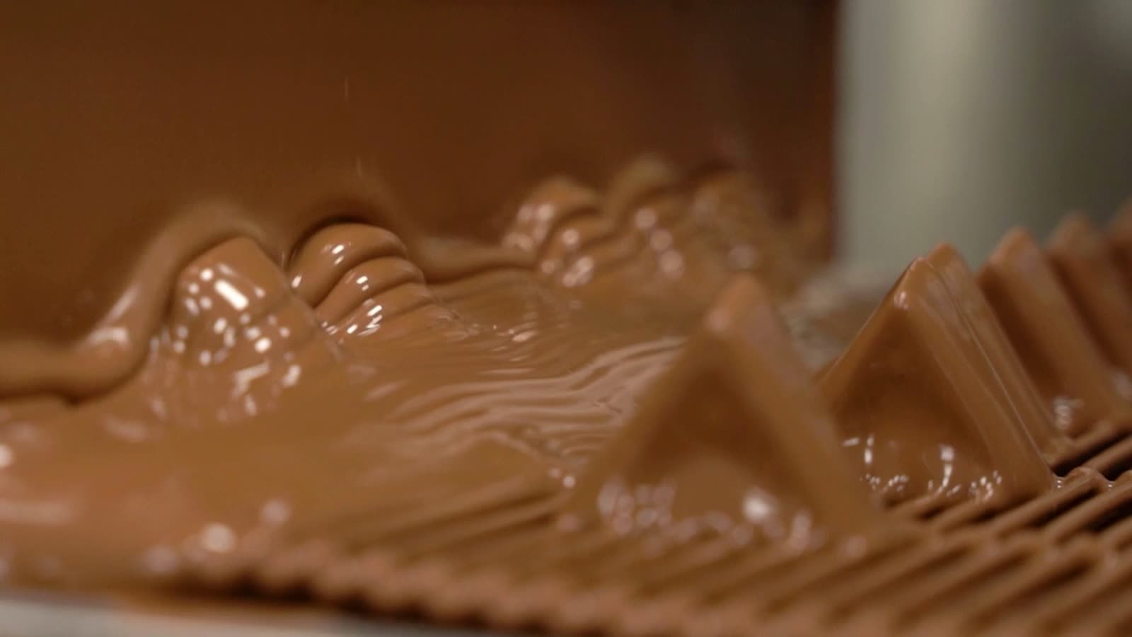 A curtain of chocolate coating pieces on the EDC enrobing line